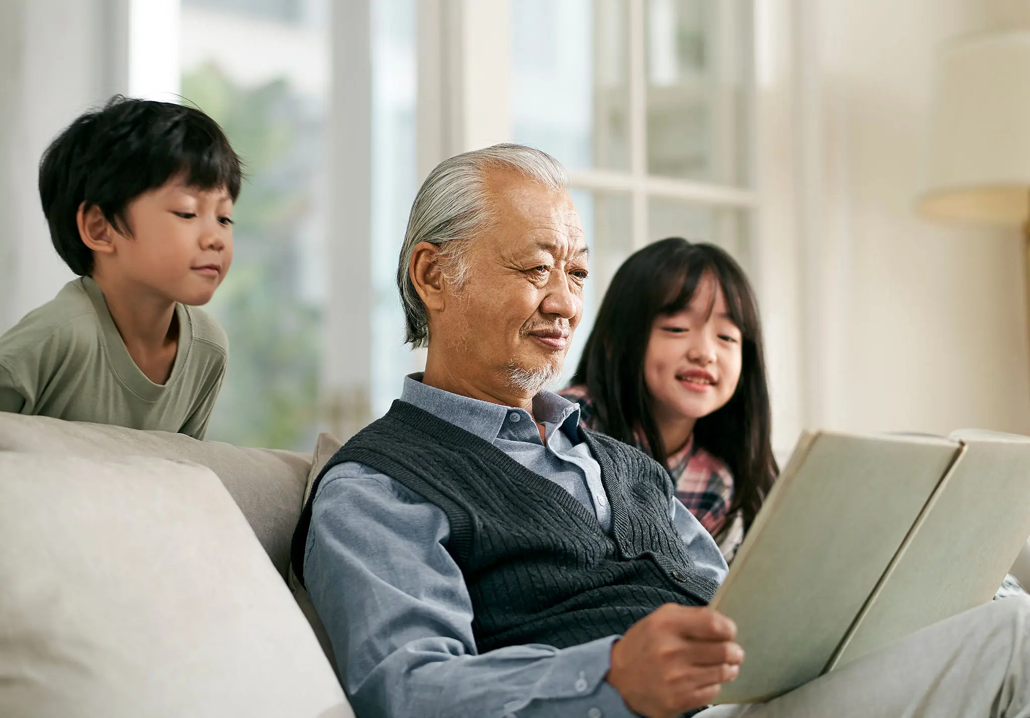 Family sitting on couch reading a book.